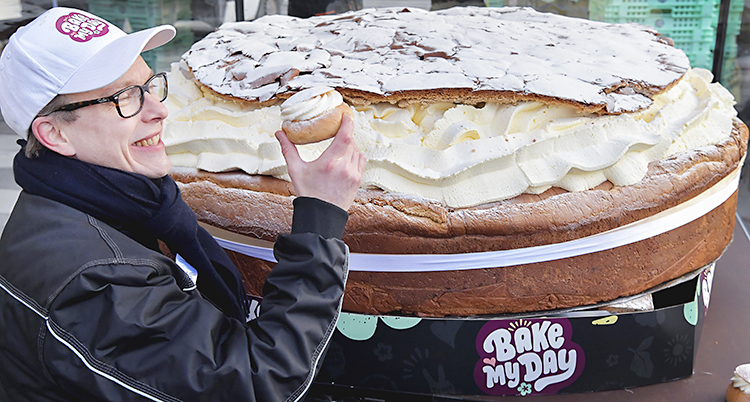 Han ser glad ut och håller upp en liten semla framför den stora
