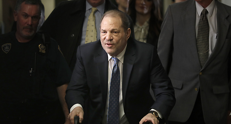 Bilden visar hur Harvey Weinstein kommer till en domstol. Han går med en rullator. Han har på sig en mörk kostym och slips.
