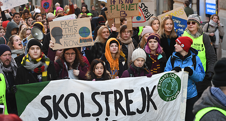 Greta Thunberg och flera andra elever går tillsammans. De har skyltar i händerna.