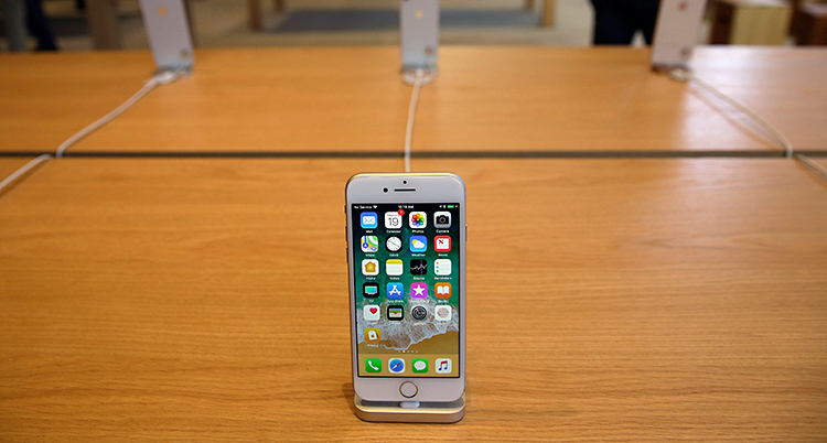 En mobiltelefon från företaget Apple står på ett bord av trä.