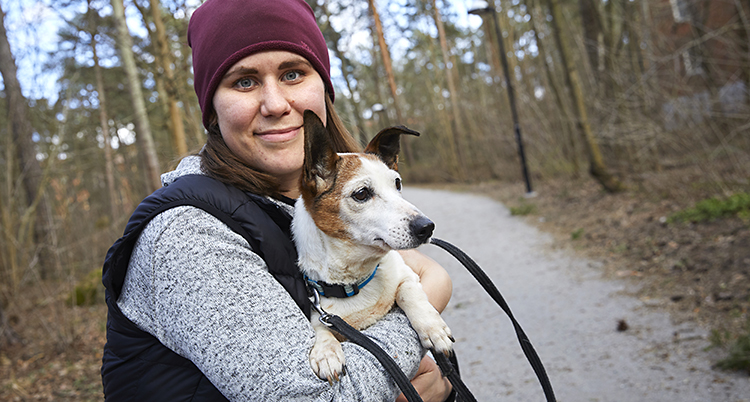En glad kvinna med en hund i famnen.