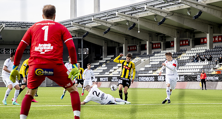 Häcken anfaller. En spelare försöker att skjuta. En back ligger ner och försöker att stoppa honom.