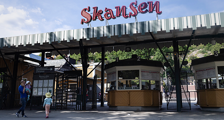 Det är en solig dag. En vuxen och två barn står utanför ingången till Skansen.