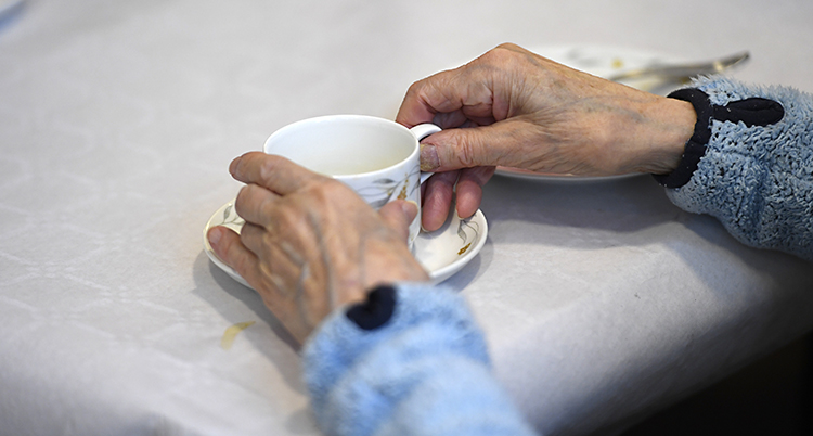 Två gamla händer håller i en kaffekopp