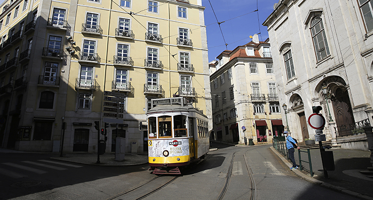 En öde gata i Portugal. En spårvagn åker på ett spår på en gata. En ensam man med munskydd syns på gatan.