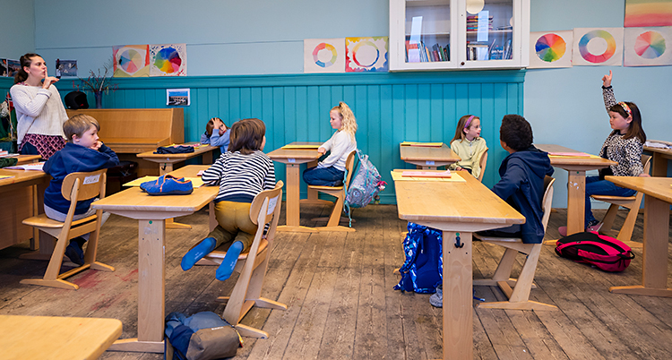 Ett klassrum. En lärare står upp. Flera elever sitter i sina bänkar. De går i tredje klass.