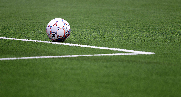Bilden visar en fotboll som ligger på en fotbollsplan.
