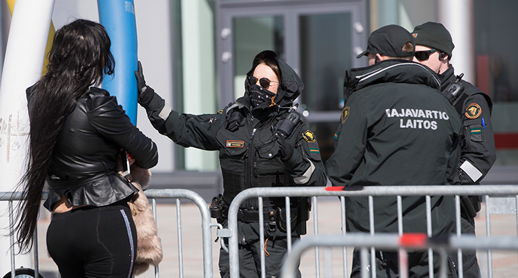 Tre finländska poliser vid ett staket. En ung kvinna står på andra sidan staketet.