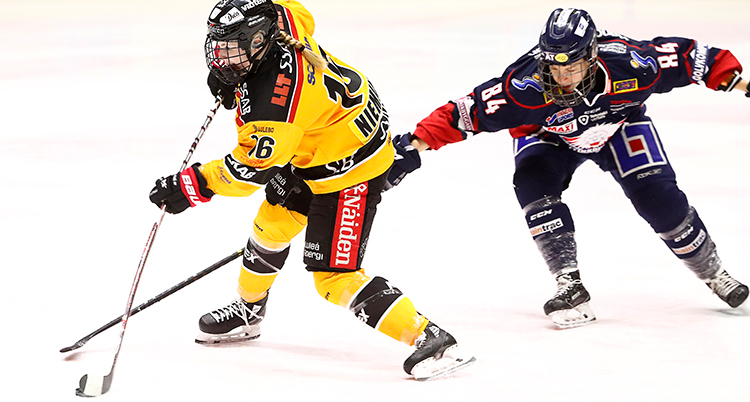Petra skjuter ett skott. En spelare sträcker fram klubban och försöker att hindra det.