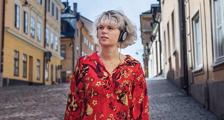 En kvinna går på en gata med hörlurar på sig.