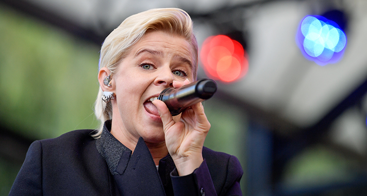 Robyn under ett framträdande med mikrofonen mot munnen.