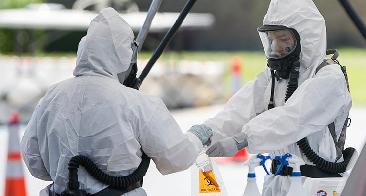 Två personer har skyddskläder och masker för ansiktet.