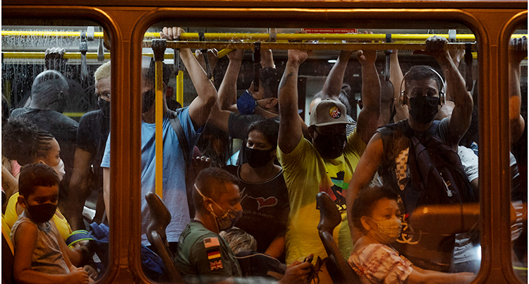 Människor trängs på en buss i Brasilien. Många har på sig munskydd.