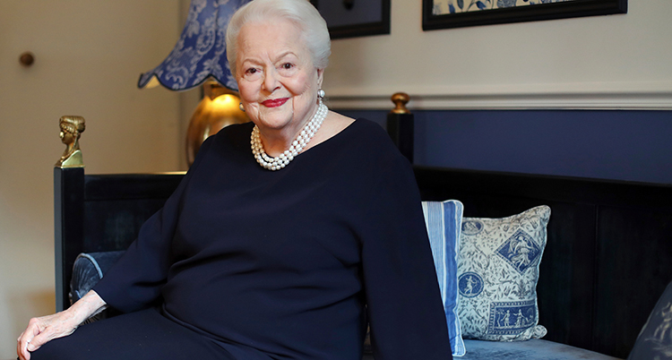 Olivia de Havilland i blå klänning, pärlhalsband i sitt hem. Bilden är från 2016.
