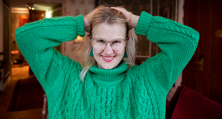 Emma Örtlund har på sig en grön tröja. Hon drar händerna genom håret.