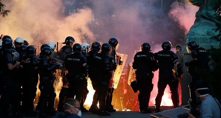En grupp poliser vaktar en demonstration i Belgrad. I bakgrunden syns mycket rök.