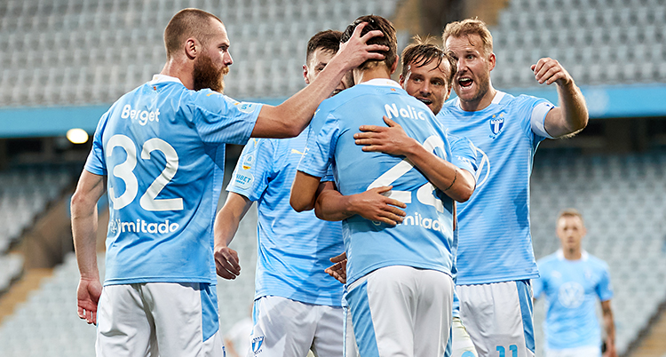 Flera fotbollsspelare kramas. De har vita shorts och ljusblå tröjor.