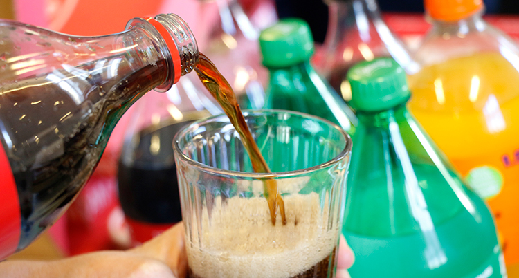 Någon häller upp coca cola i ett glas.