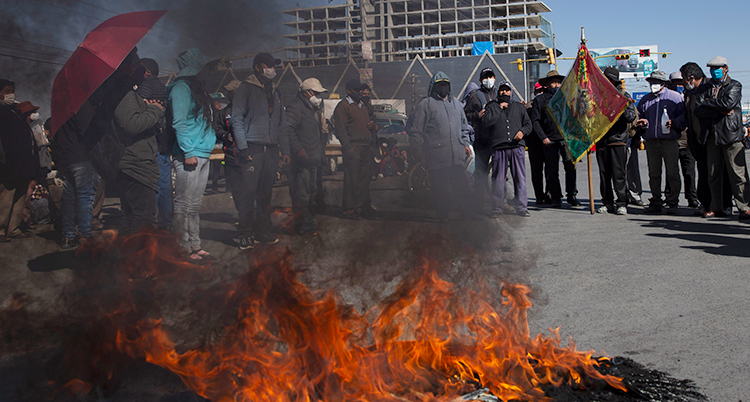 Några demonstranter i Bolivia bränner bildäck. Bakom elden syns en grupp demonstranter som står i en klunga.