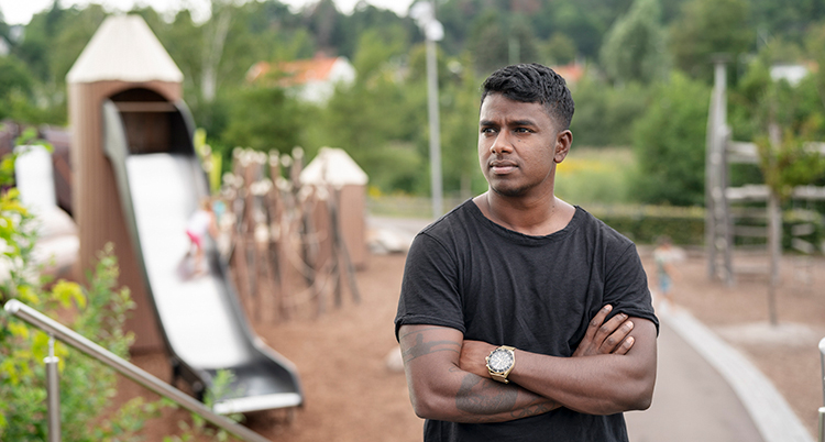 Han har svart t-shirt och tatueringar på armarna.