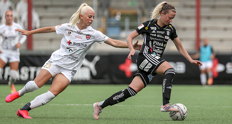 Två spelare. Piteås spelare har bollen. En annan spelare försöker att komma ifatt. De Men hon är på väg att springa ifrån.
