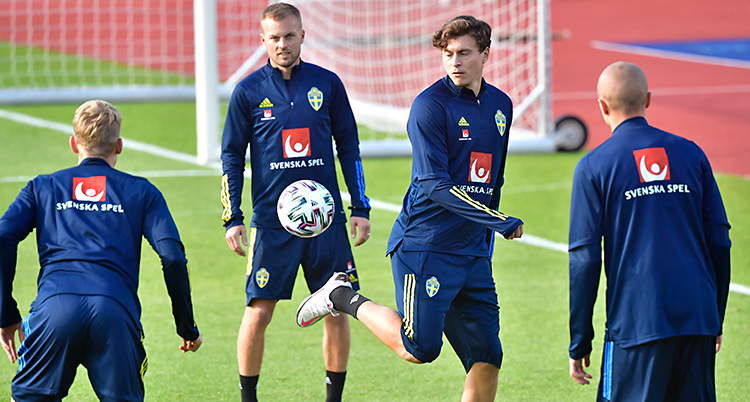 Fyra män är på en fotbollsplan. En av dem klackar bollen. De har på sig blå dräkter.