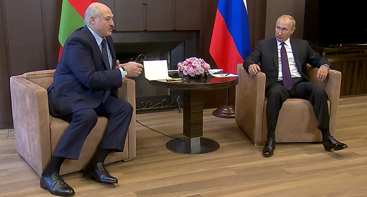 Lukasjenko sitter i en fåtölj vid ett litet bord. På andra sidan bordet sitter Putin.
