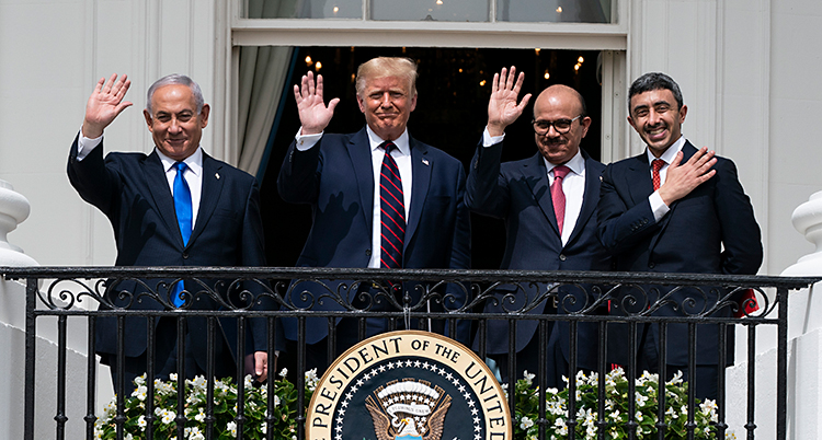 Fyra män står på en balkong och vinkar. På balkongen finns ett märke där det står United States of America.