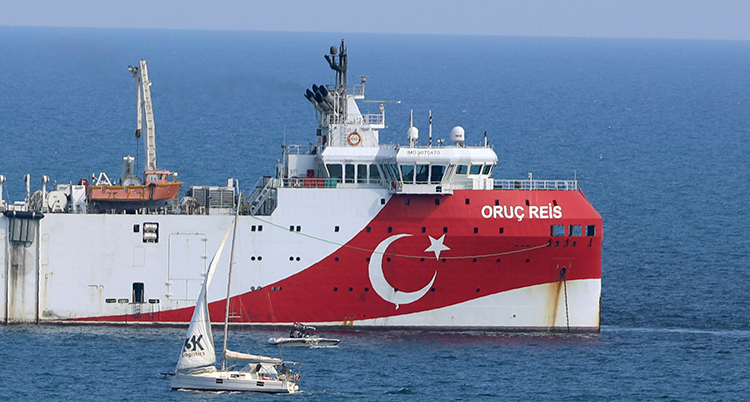 Ett stort fartyg. Det är rött och vitt med Turkiets symbol, en halvmåne och en stjärna, målat på det röda. Framför skeppet är en liten segelbåt.