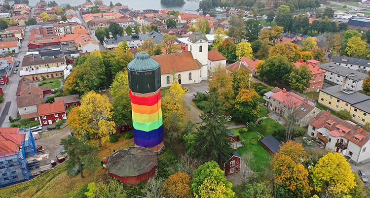 Ett torn invirat i en stor flagga i regnbågens färger.