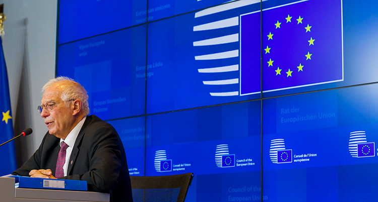 EUs utrikeschef Josep Borrell sitter vid podiet framför en blå skärm med EUs flagga.