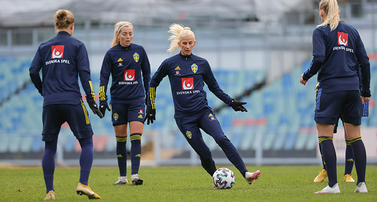 Fyra spelare passar bollen till varandra. De är klädda i blå träningskläder.