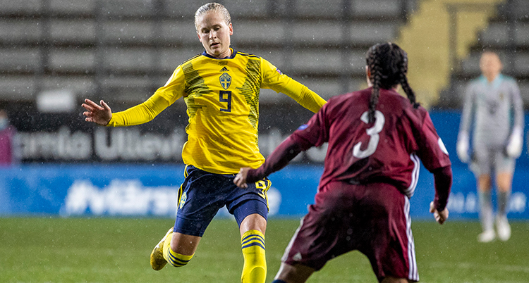 en fotbollsspelare i gul tröja möter en fotbollspelare i vinröd tröja