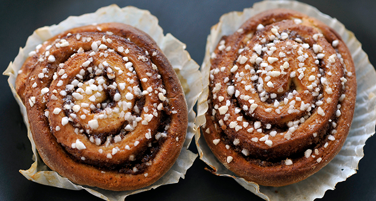 Två kanelbullar i vita bullformar.