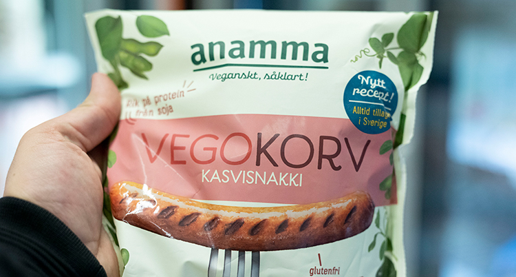 en hand håller i en påse som det står vegokorv på
