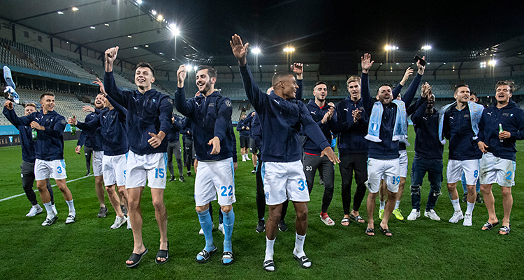 Flera män är på en fotbollsplan. De är glada och och dansar. De är spelare i Malmö FF.