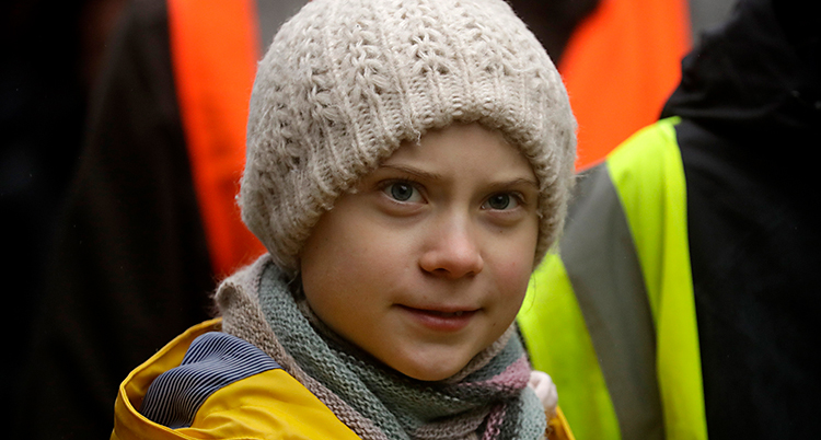 Greta Thunberg på en strejk för klimatet. Hon har en vit mössa och en gul regnjacka.