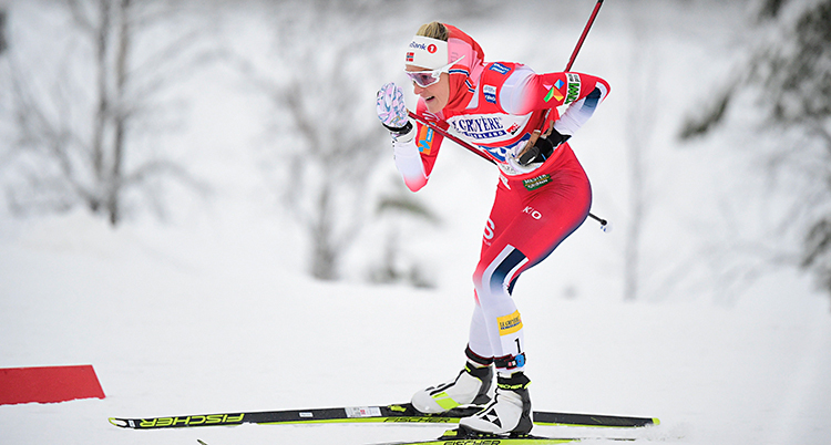 Therese Johaug åker skidor. Hon har en röd och vit dräkt.