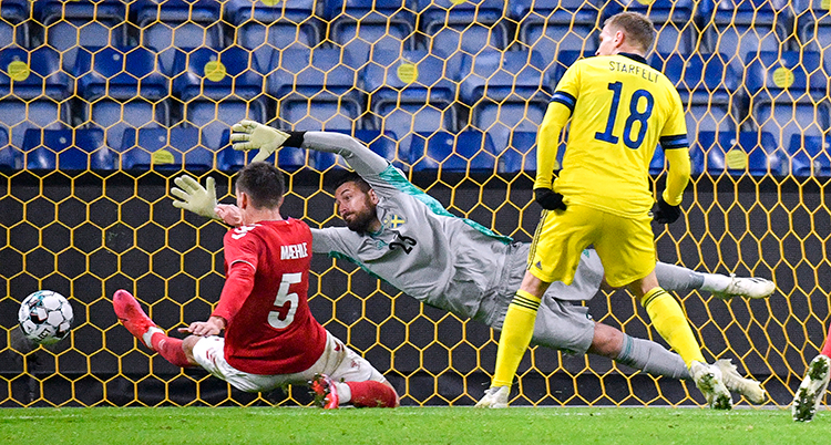 En svensk spelare ser på när en dansk kastar sig fram och skjuter bollen i mål. Svenske målvakten kastar sig raklång men han når inte fram till bollen.