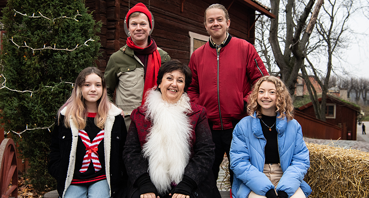 Ett foto på hela gruppen. De sitter och står utomhus. Bakom dem syns en julgran.