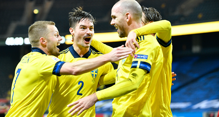 Fyra fotbollsspelare i gula landslagströjor klappar om varandra och jublar