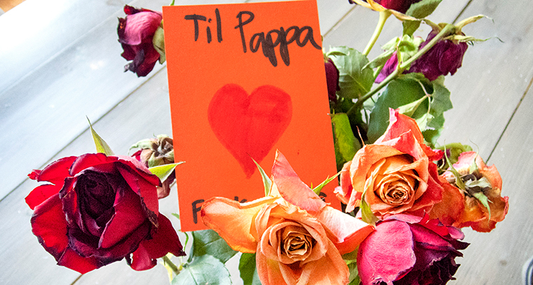 en blombukett med rosor i olika färger och ett orange kort i buketten med texten Til Pappa