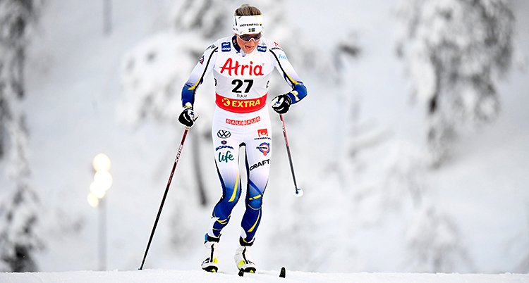 Frida Karlsson åker skidor i ett spår. Det är snö runtomkring.