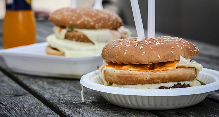 Vi ser ett bord. På bordet står två papptallrikar. På varje tallrik finns en hamburgare.