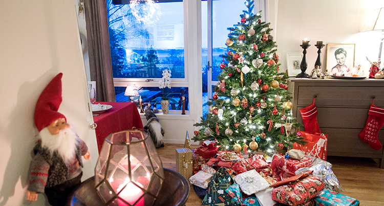 Ett vardagsrum med julpynt, paket och en julgran