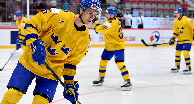 Ishockeyspelare i landslagsdräkter åker på isen i en ishall