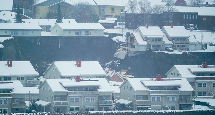 En suddig bild som visar ett område med flera villor. Mitt i bilden är det svart. Det är ett stort långt hål. Några hus har rasat ner.