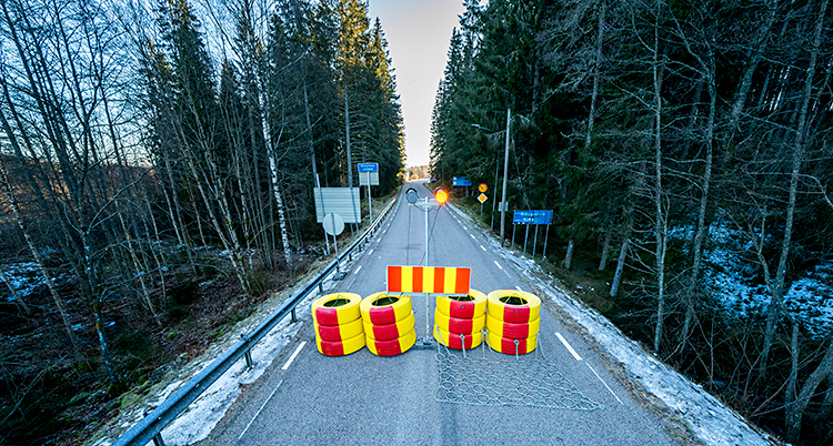 Bilden visar en väg för bilar. Vägen är spärrad med däck. Däcken är målade i rött och gult.