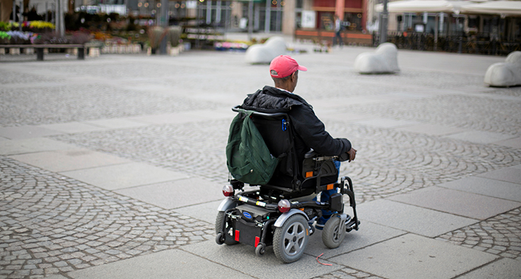 En man i permobil kör över ett öde stentorg