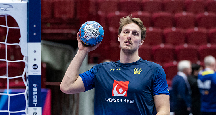 En spelare håller upp bollen. Han ser lite trött ut.